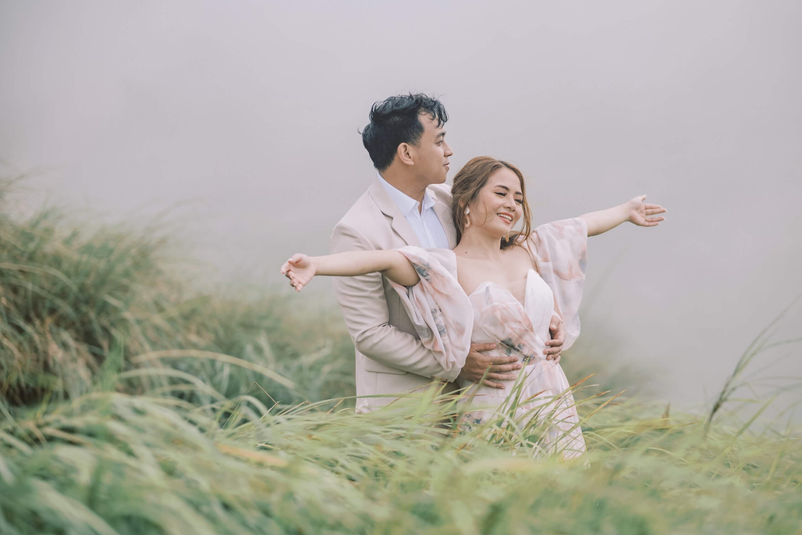 Newlyweds posing outdoors with greenery